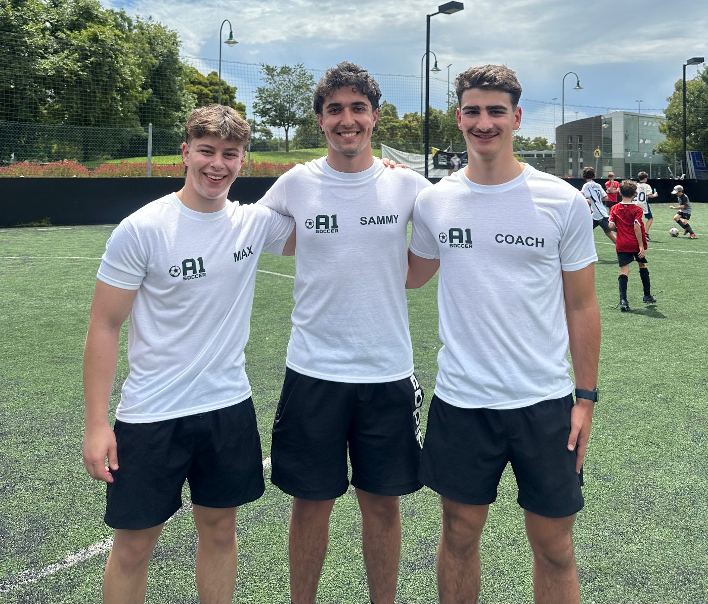 Sammy and two A1 coaches smiling on the pitch