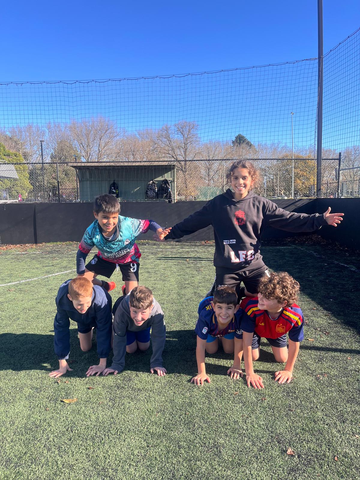 Six players making a human pyramid, all grinning